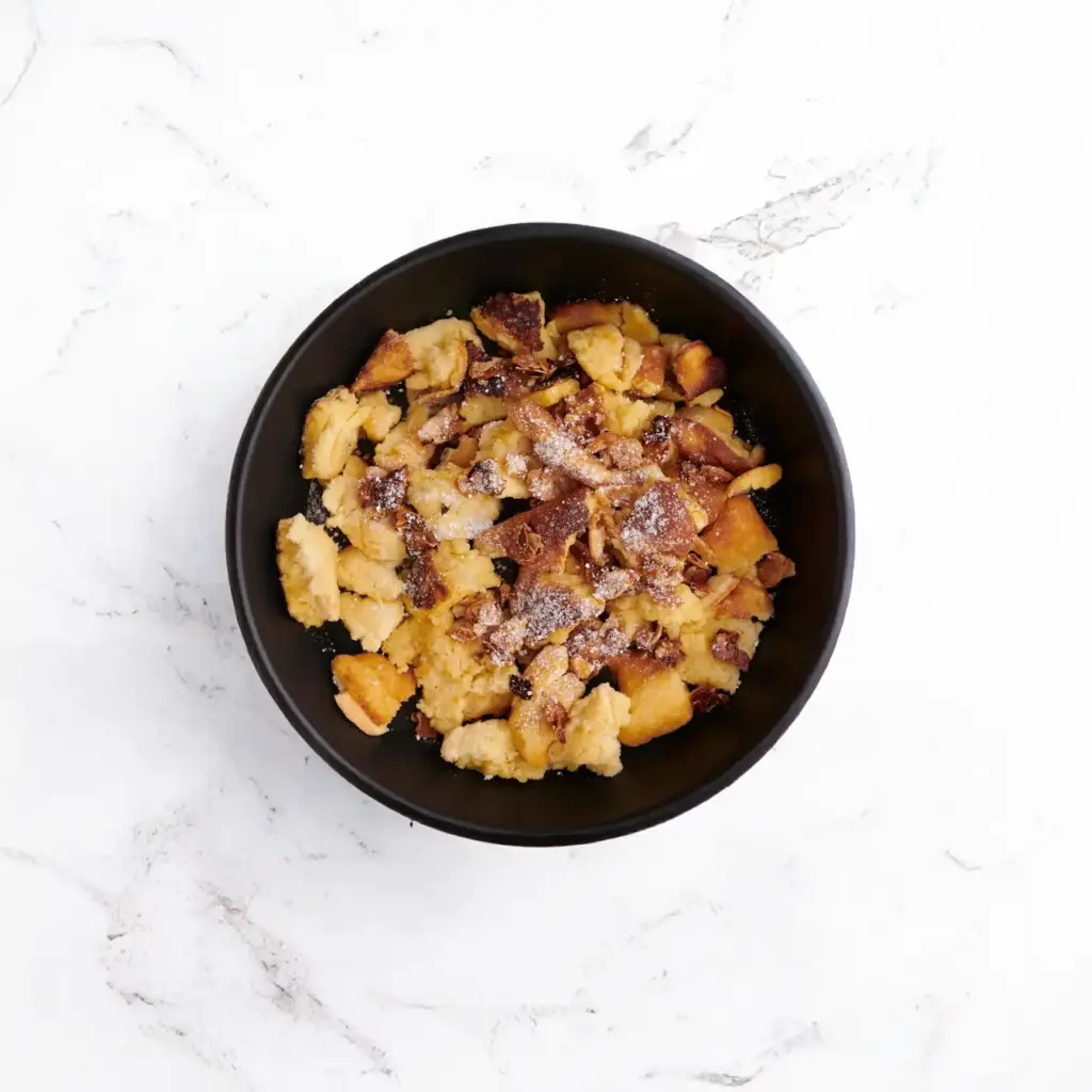 Weihnachtlicher Kaiserschmarrn mit Weichselröster und Mandelkrokant auf weißem Teller - Privatkoch Aachen
